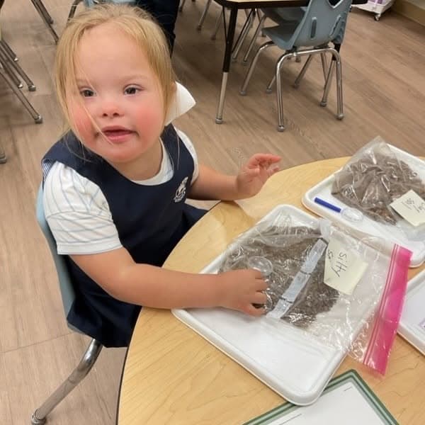 Preschool student exploring soil samples through sensory play and scientific investigation while developing curiosity and critical thinking skills.