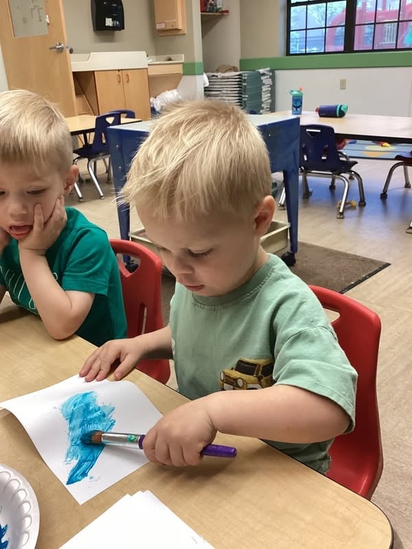 Preschooler painting with a brush during a hands-on classroom art activity that supports creativity, coordination, and fine motor development at Primrose School.
