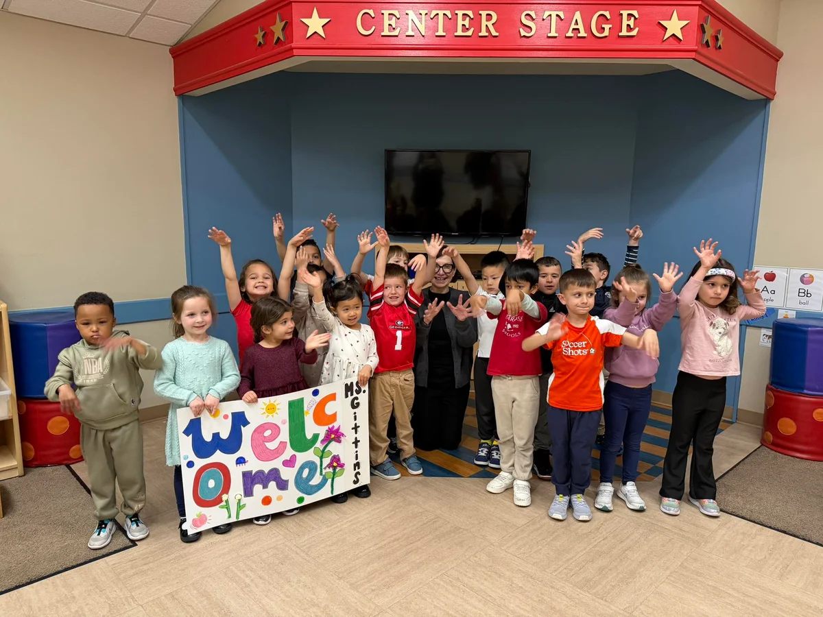 children standing with an adult holding a welcome sign