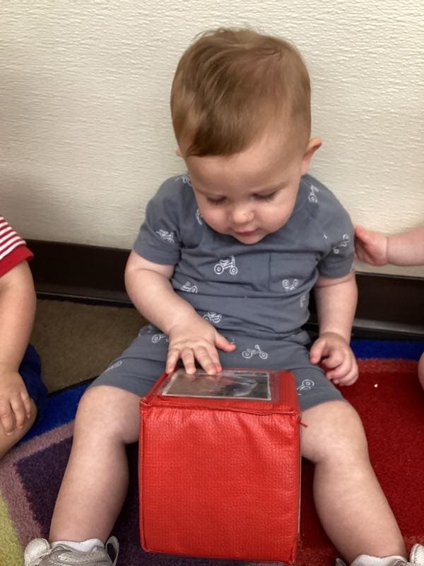 Infant exploring a soft sensory cube while building tactile awareness, focus, and early cognitive skills.