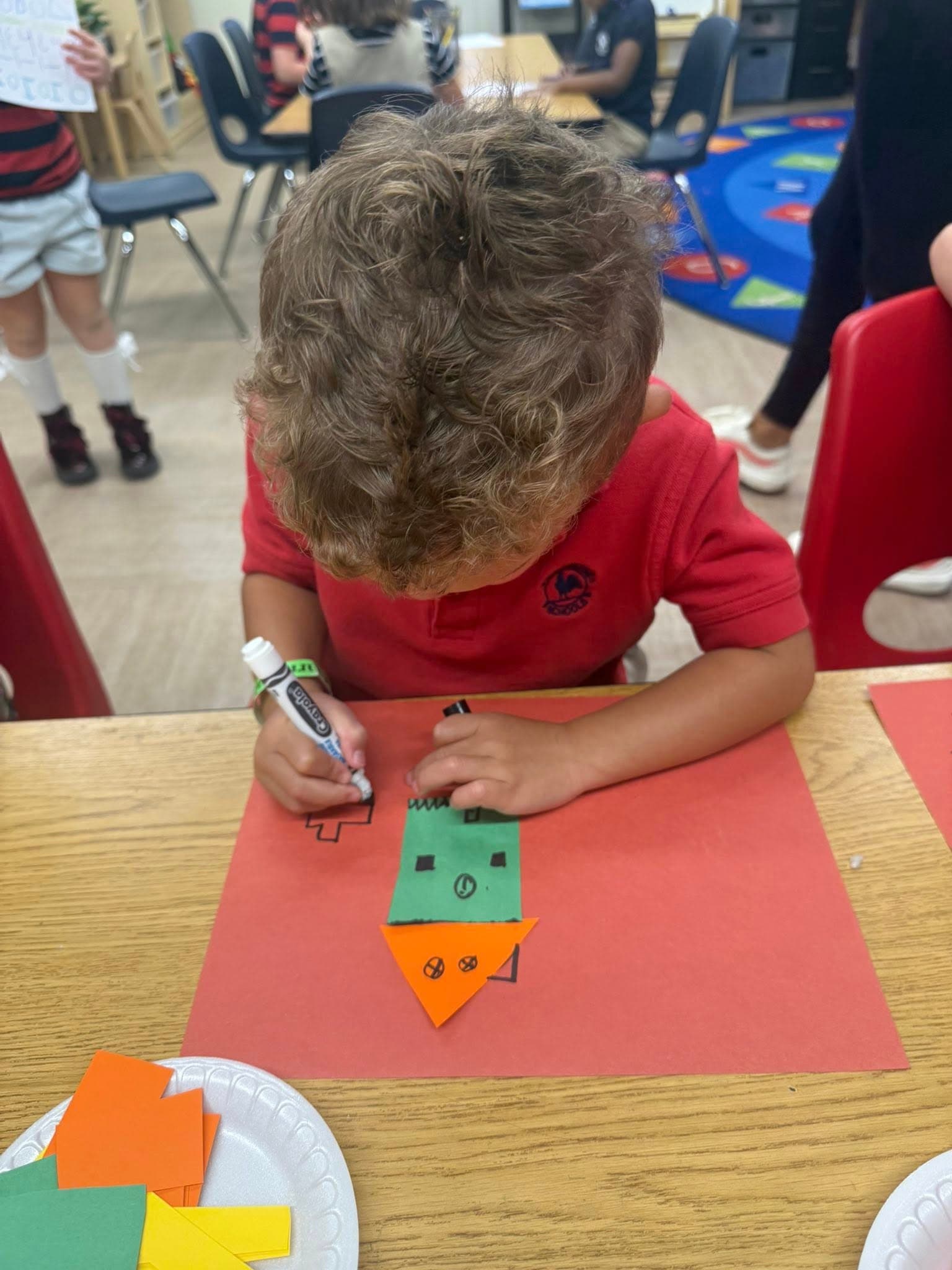 Student creating a shape monster craft while practicing geometry, creativity, and fine motor skills.