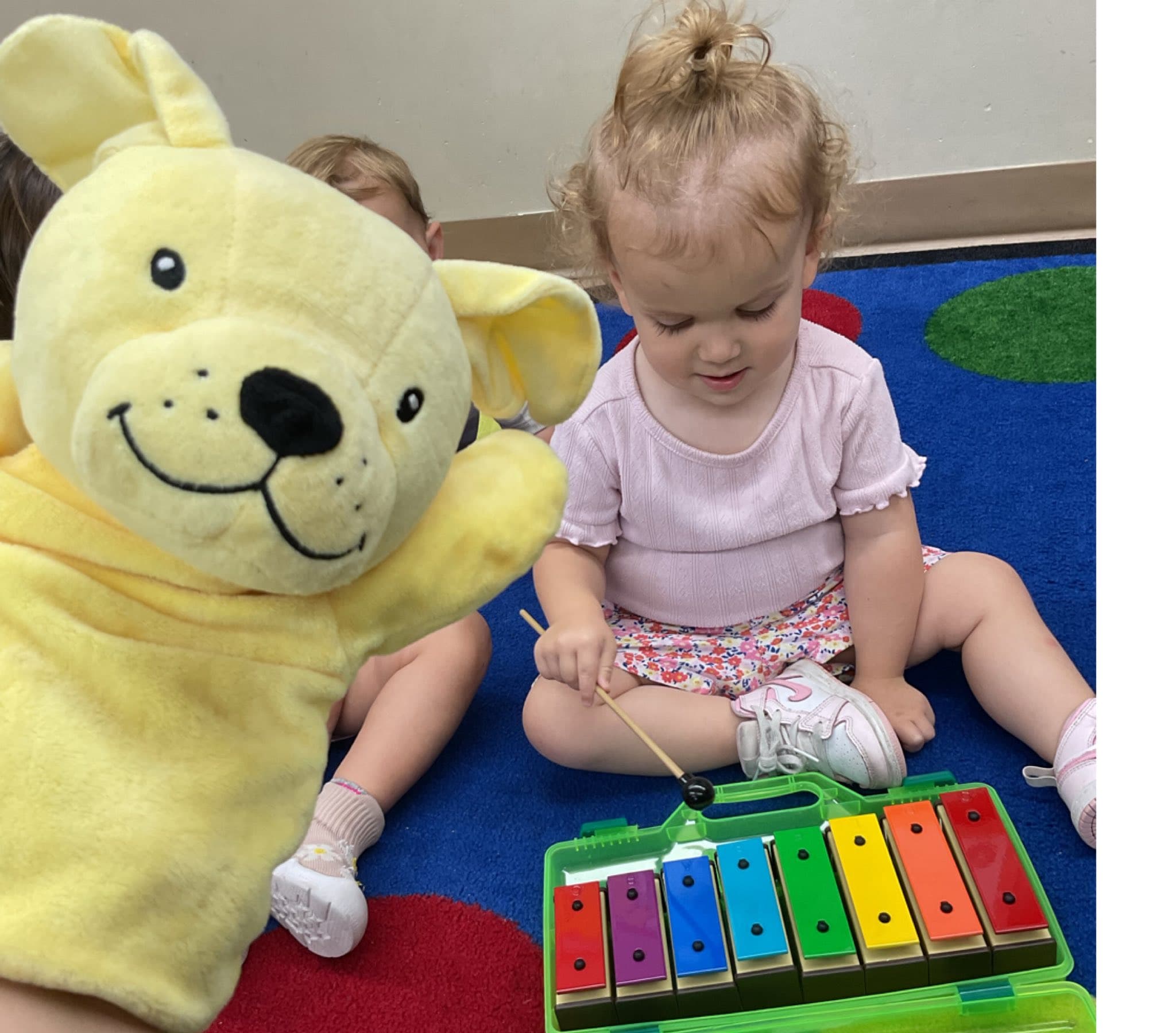 Toddler playing a colorful xylophone while exploring sounds, rhythm, and musical expression in the classroom.