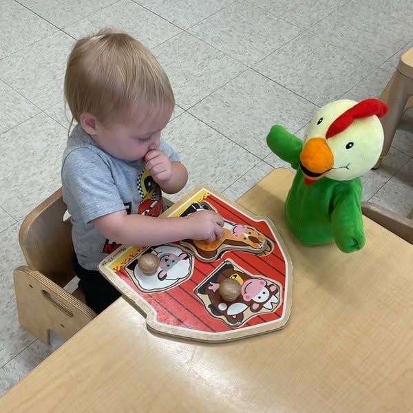 Toddler completing a farm animal puzzle to develop fine motor skills, hand-eye coordination, critical thinking, and early cognitive development at Primrose School.