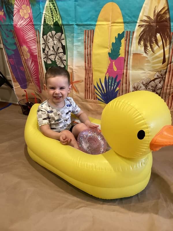boy sitting on blow up rubber duck