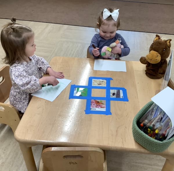 Toddlers participating in literacy and writing skills in a safe classroom at Alliance childcare facility