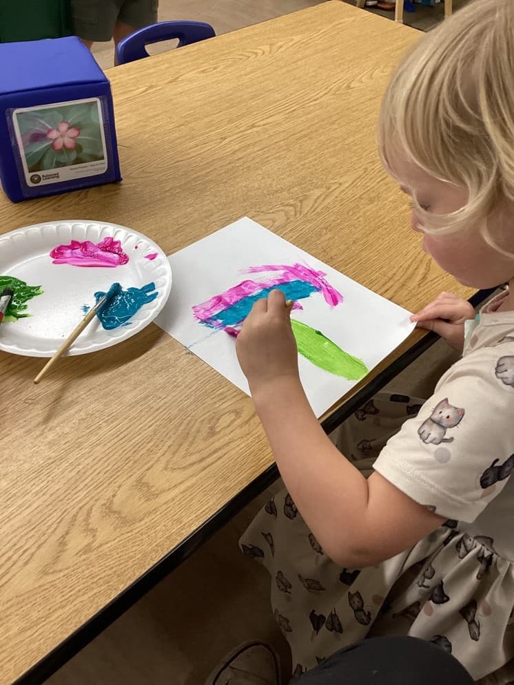 Child creating a colorful painting while exploring colors, creativity, and artistic expression.