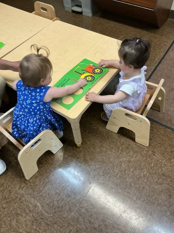 Two toddlers working together on an interactive learning activity that encourages teamwork, communication, problem-solving, and fine motor development at Primrose School.