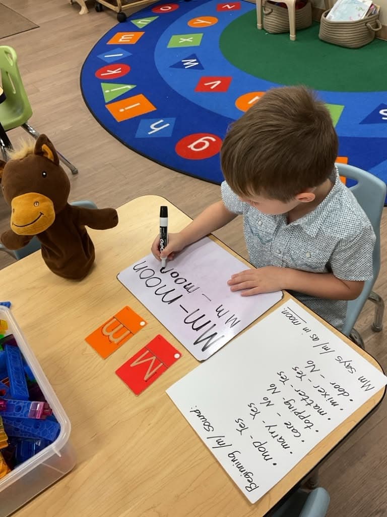 Student practicing letter formation and handwriting on a dry-erase board while strengthening literacy, fine motor skills, and letter recognition.