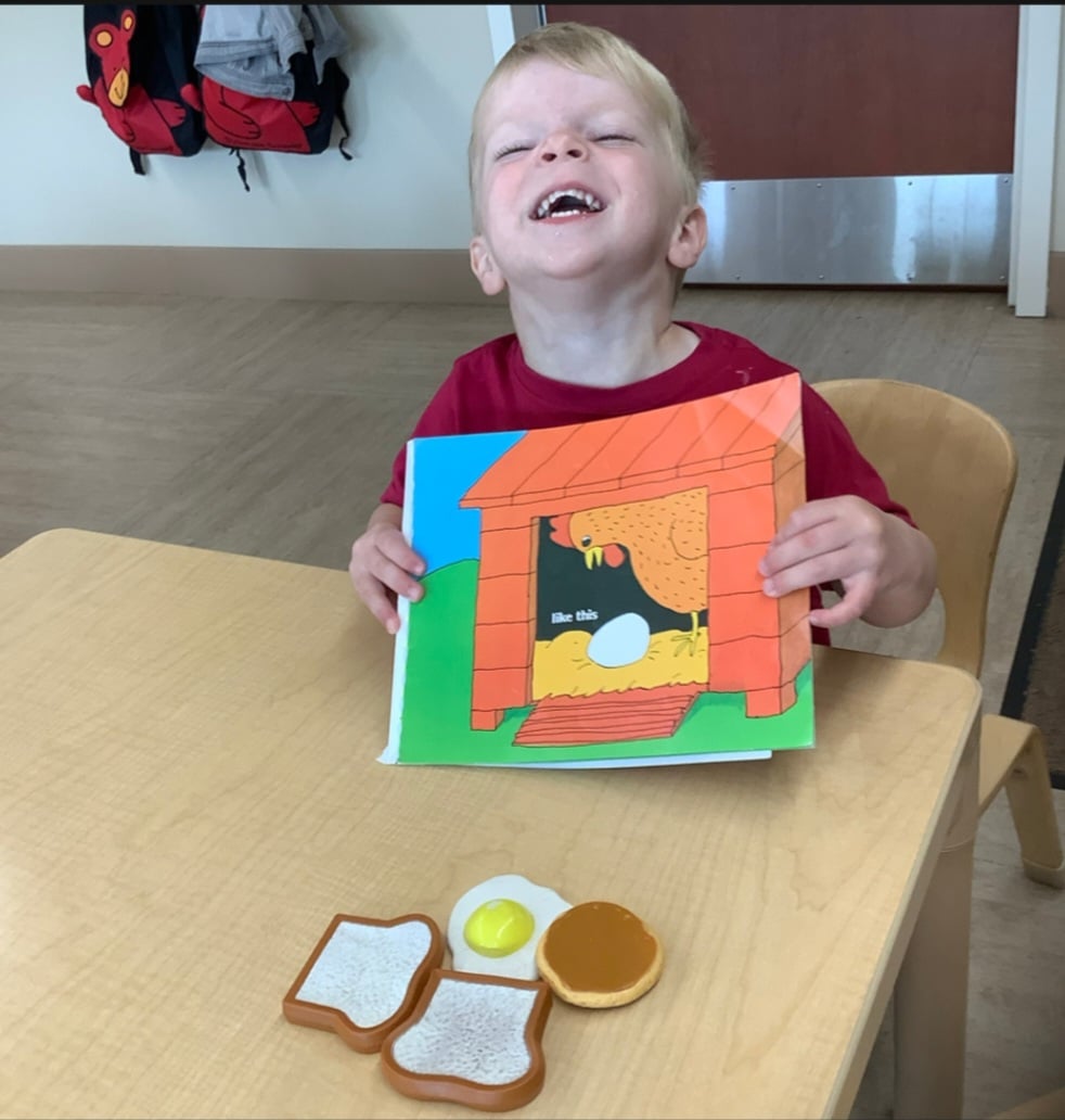 child holding book with breakfast food props in from of him
