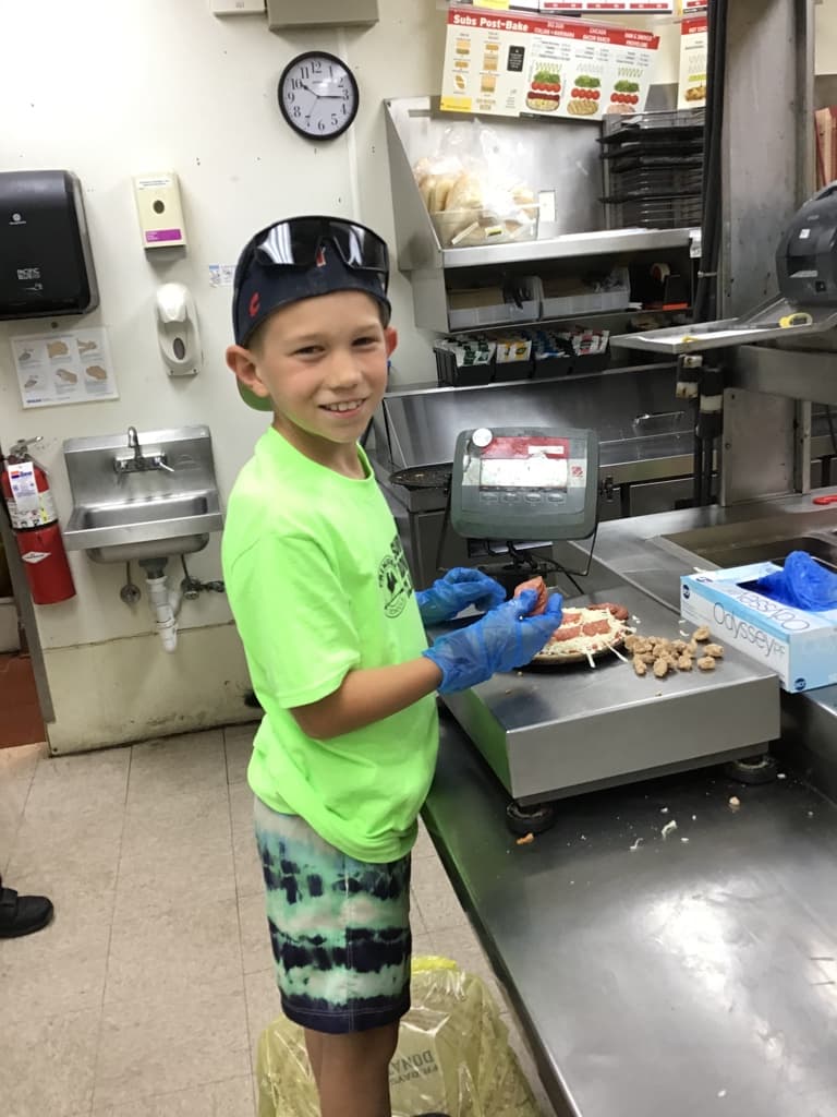 Student makes small pizza at our Donato's field trip
