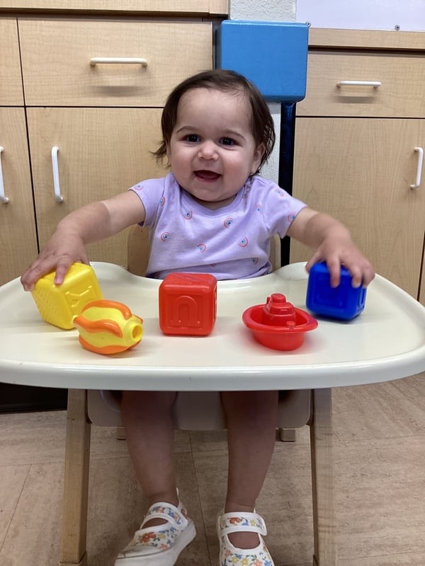 Infant playing with colorful stacking and shape toys while developing hand-eye coordination and fine motor skills through interactive play.