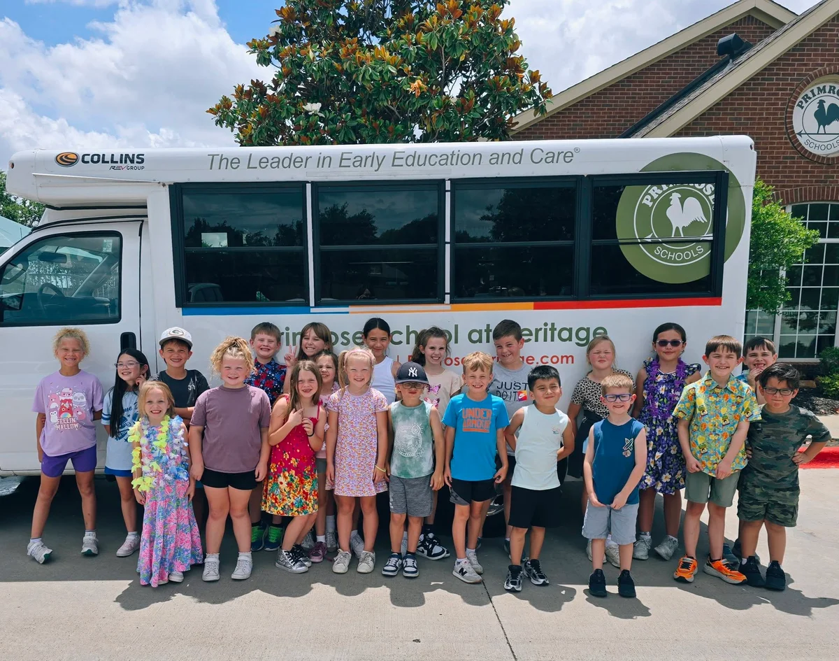 Summer Adventure Club students standing in front of the Primrose School at Heritage bus after participating in an Evacuation Drill.