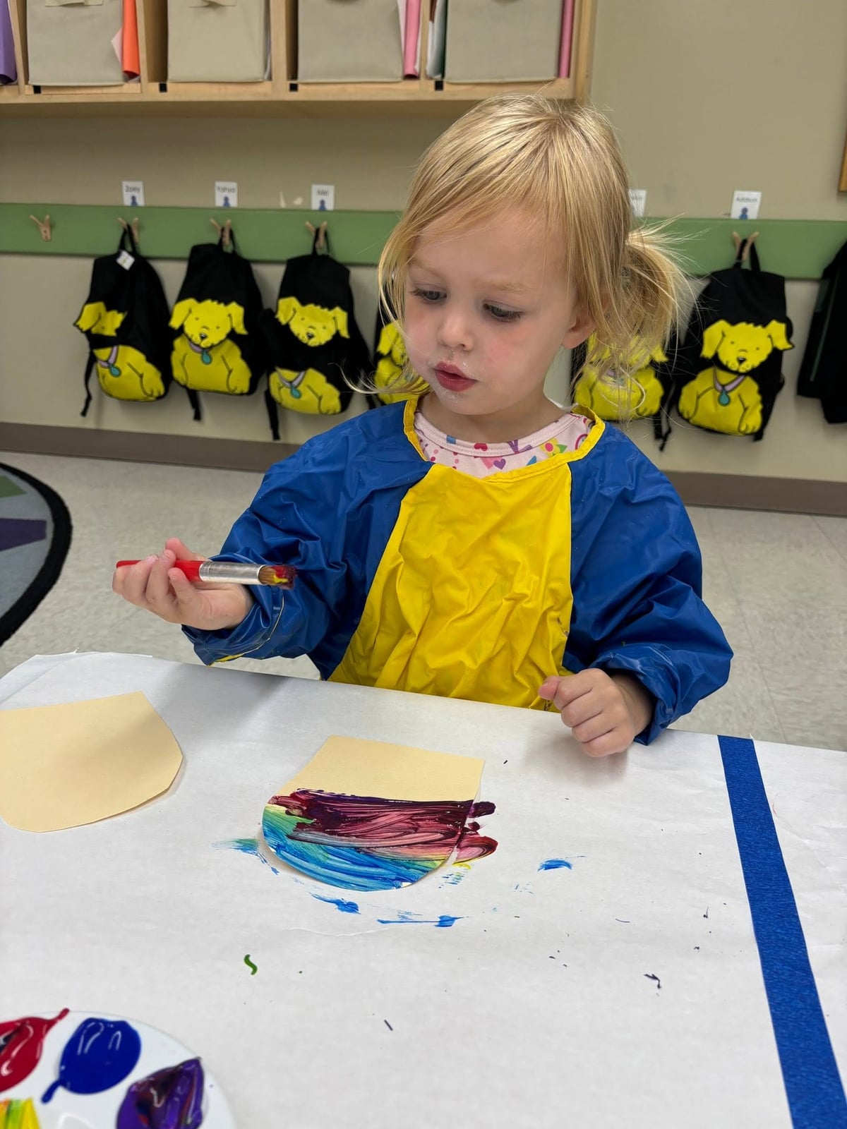 Preschooler painting a colorful art project with a paintbrush during a classroom activity that encourages creativity, self-expression, and fine motor development at Primrose School.