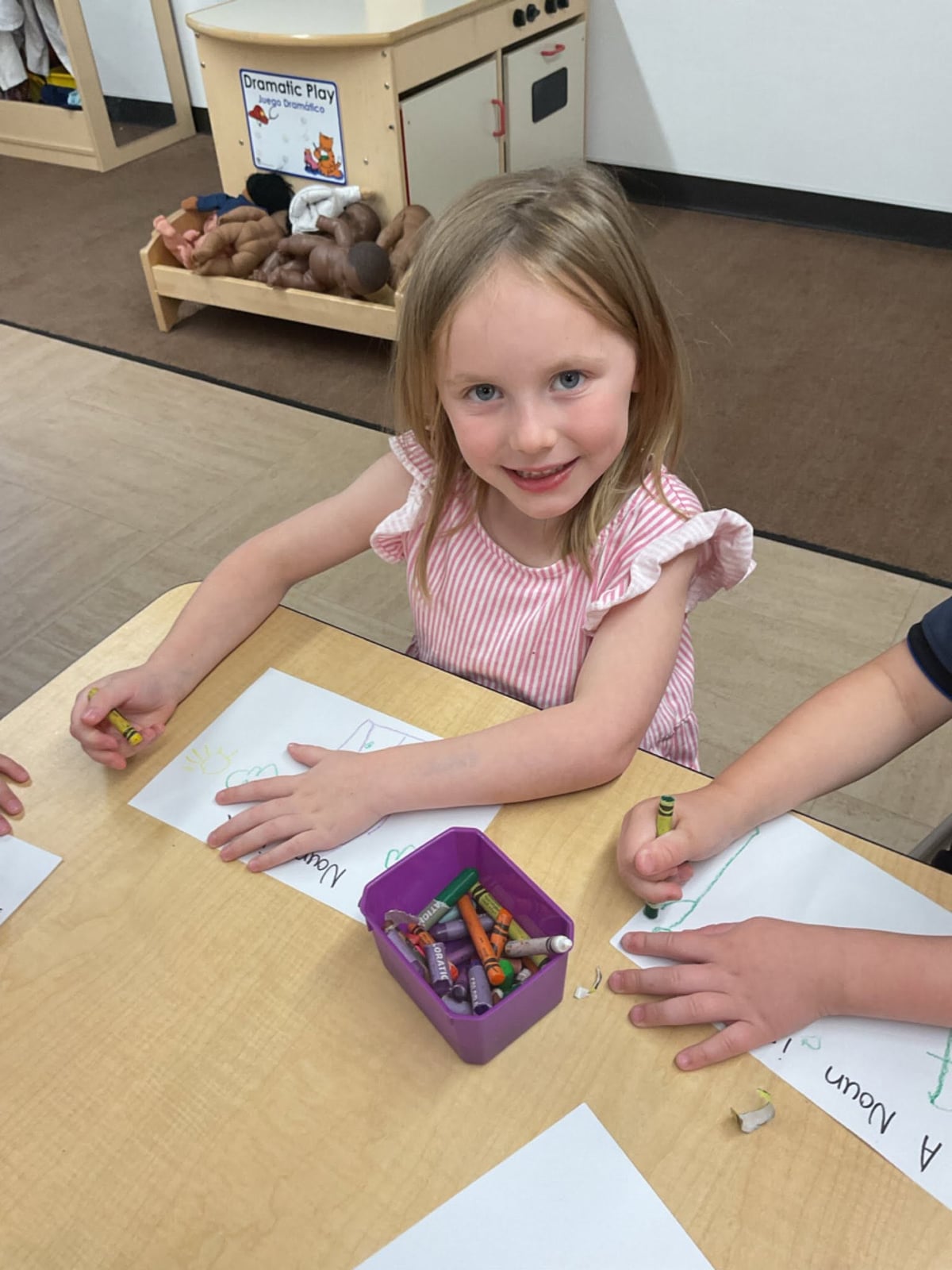 Preschool student colors a drawing with crayons while participating in a creative classroom art activity at Primrose School.