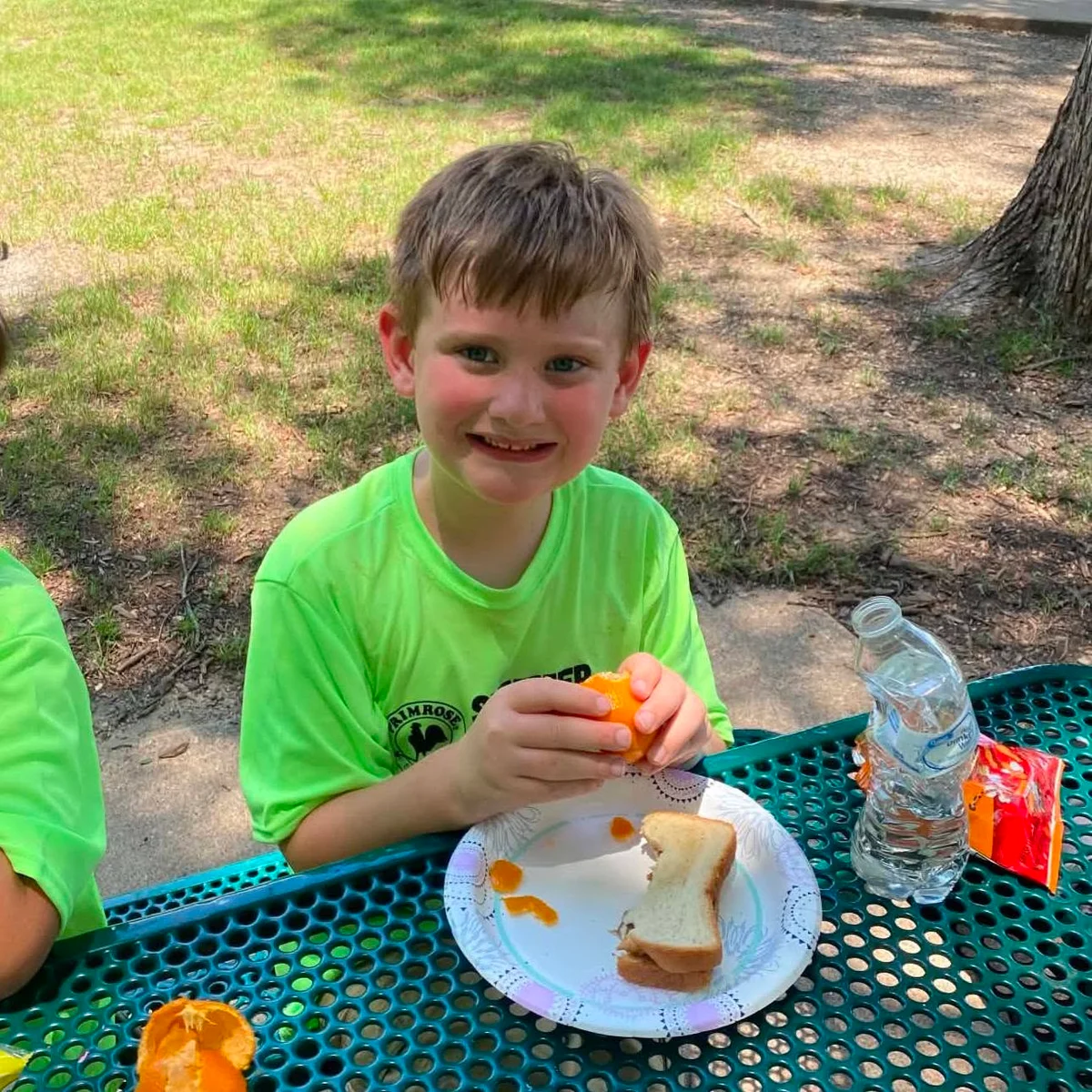 A Summer Adventure Club student eating lunch in the park on a field trip with Primrose School at Heritage.