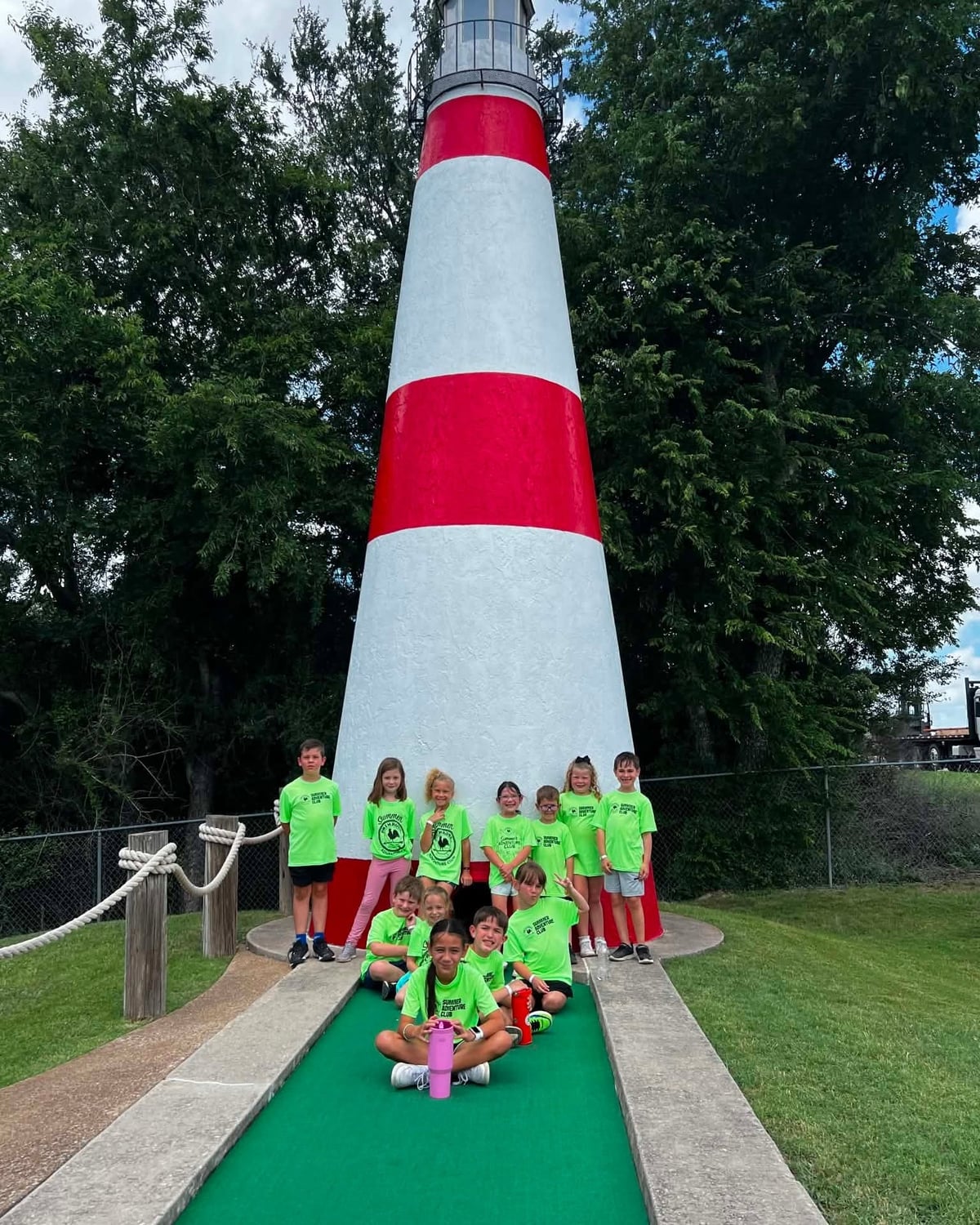 Summer Adventure Club on a fun field trip in front of a lighthouse at mini golf with Primrose School at Heritage.