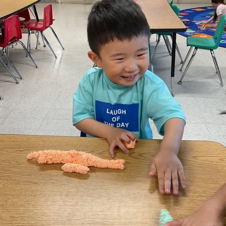 Preschool student using sensory foam to create and explore different shapes while strengthening creativity, fine motor skills, and imaginative play at Primrose School.