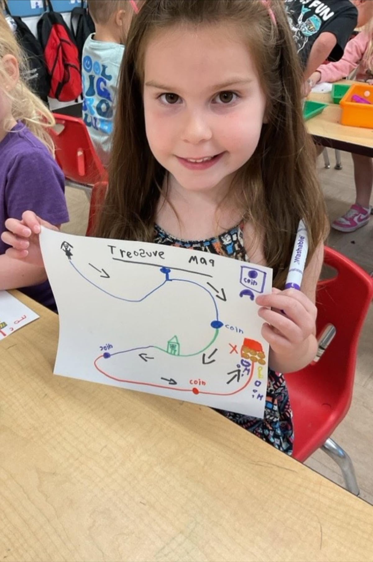 Preschool student proudly holds a handmade treasure map during a creative classroom activity that encourages imagination, drawing, and problem-solving at Primrose School.