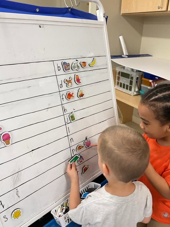 preschoolers working together on a board activity