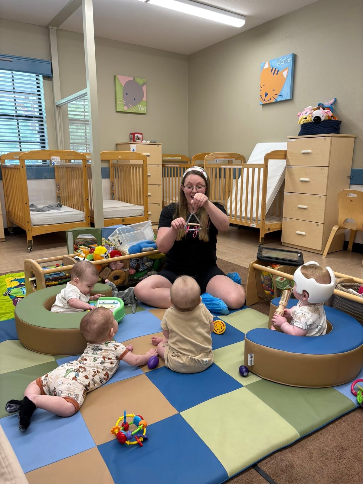 Primrose teacher engaging infants during interactive floor play and circle time with toys that encourage curiosity, movement, and early learning.