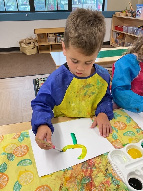 Preschool student paints a colorful picture during a hands-on art activity that encourages creativity and fine motor development at Primrose School.