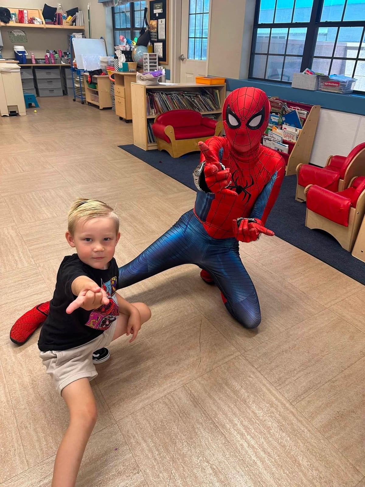 A preschool student poses alongside Spider-Man during a special character visit inside a Primrose School classroom, creating a fun and memorable experience filled with imagination and excitement.
