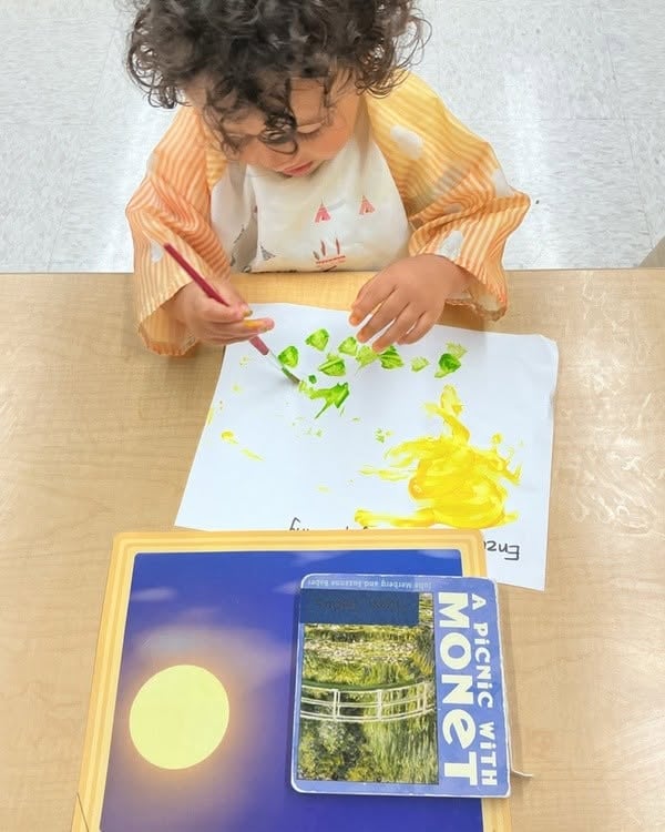 Toddler painting with a brush during a classroom art activity inspired by a children's book, encouraging creativity, color recognition, and fine motor development at Primrose School.