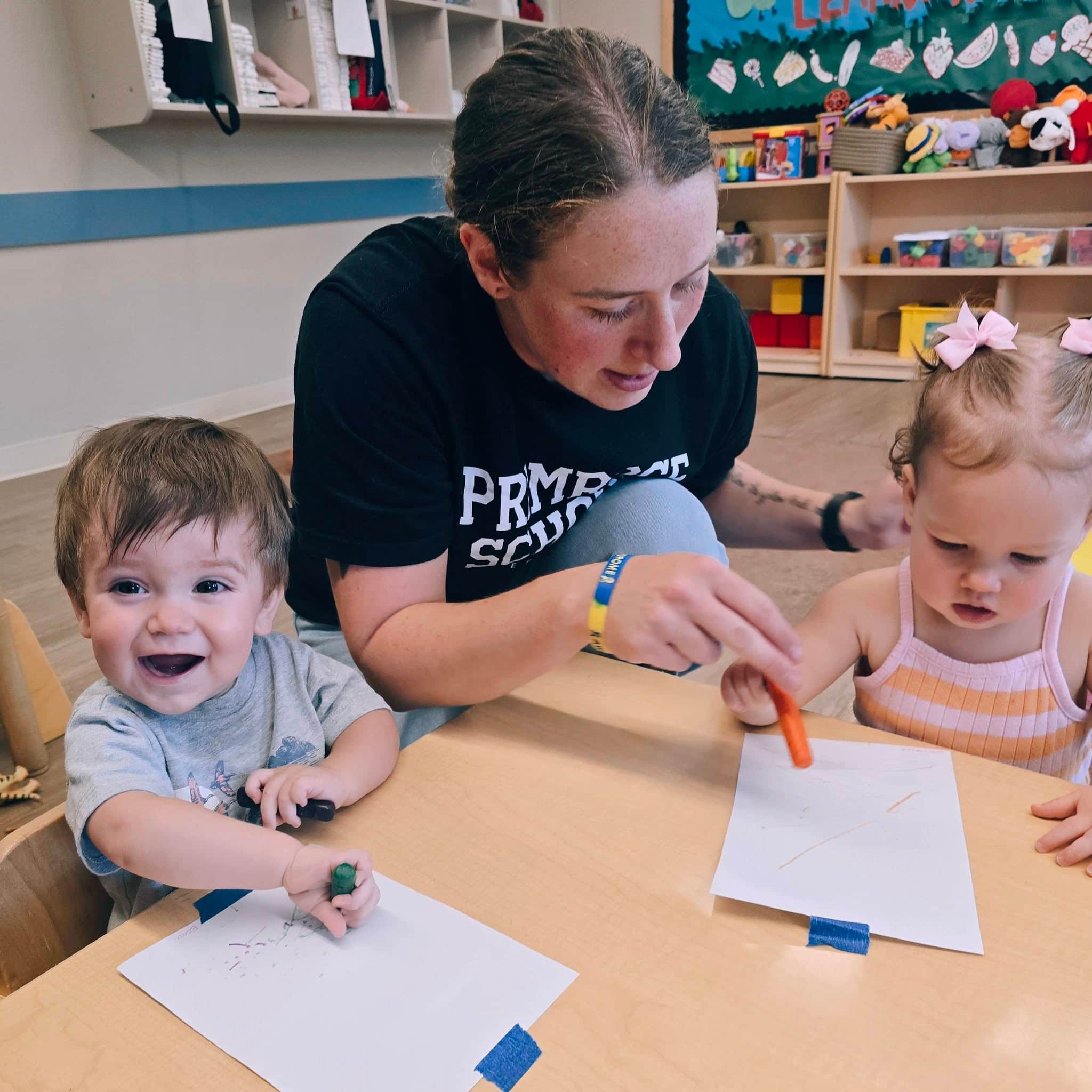 A toddler teacher engages with children in a small group at Primrose School at Heritage in Keller, TX