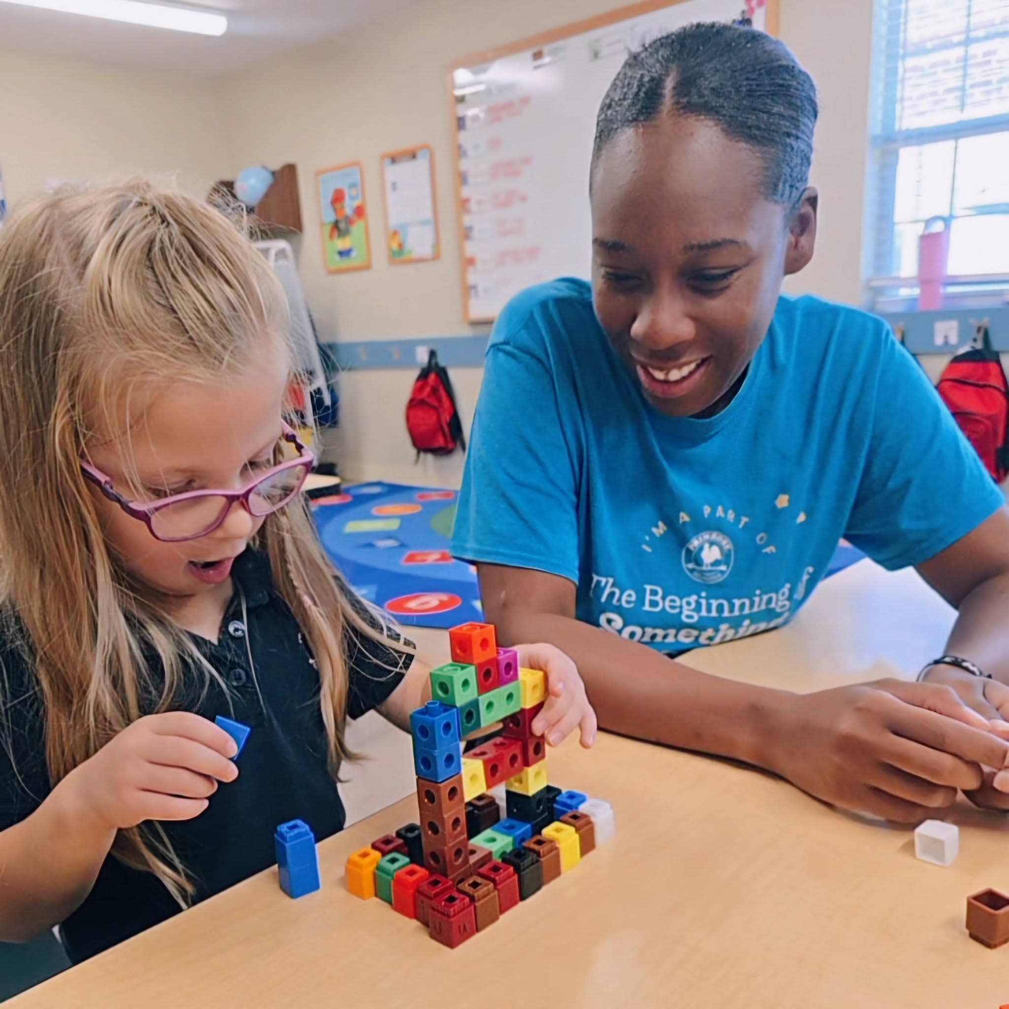 A Pre-Kindergarten student exploring math centers with her teacher's guidance and encouragement at Primrose School at Heritage in Fort Worth, TX.