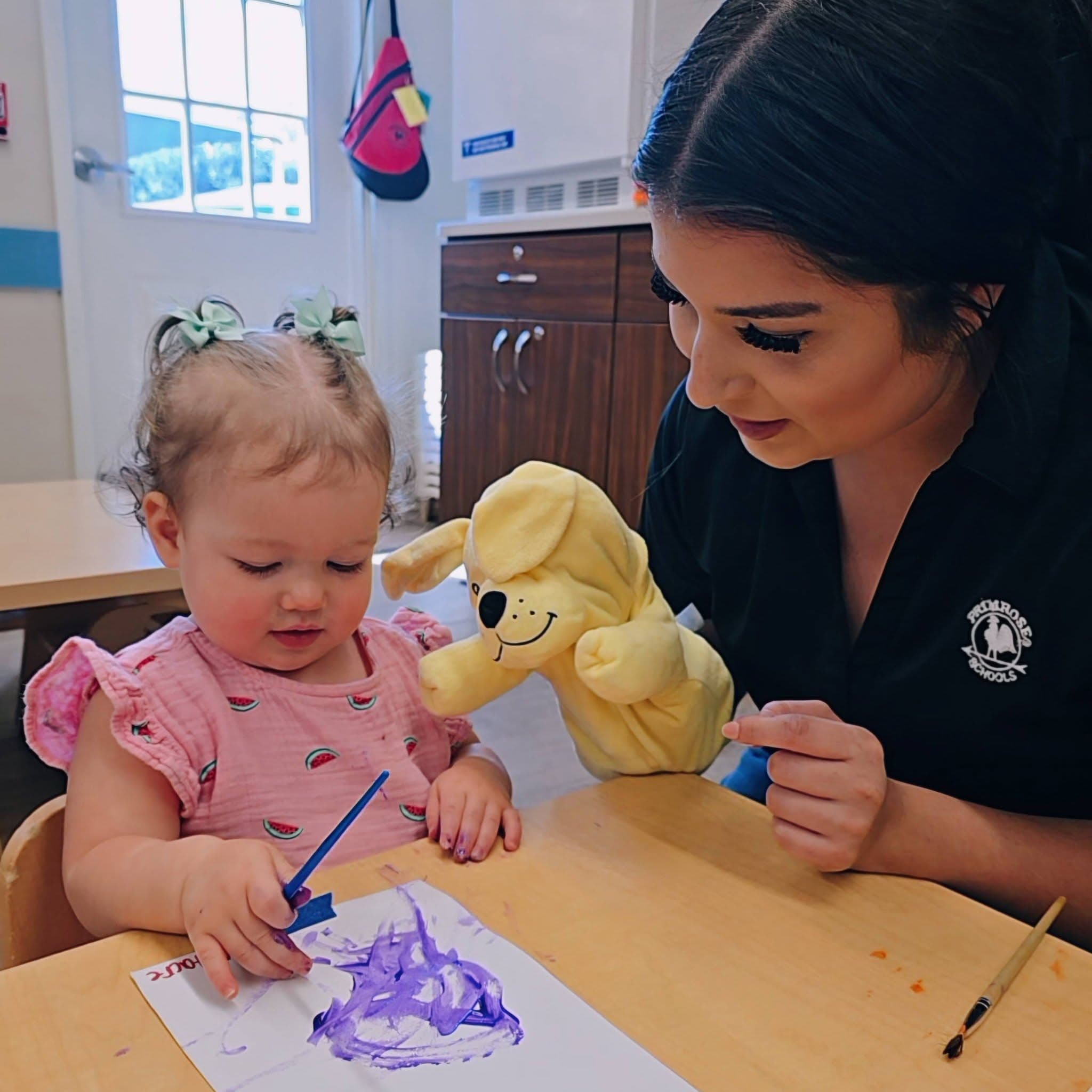 A toddler teacher encouraging her student to complete age appropriate process art at Primrose School at Heritage in Keller, TX.