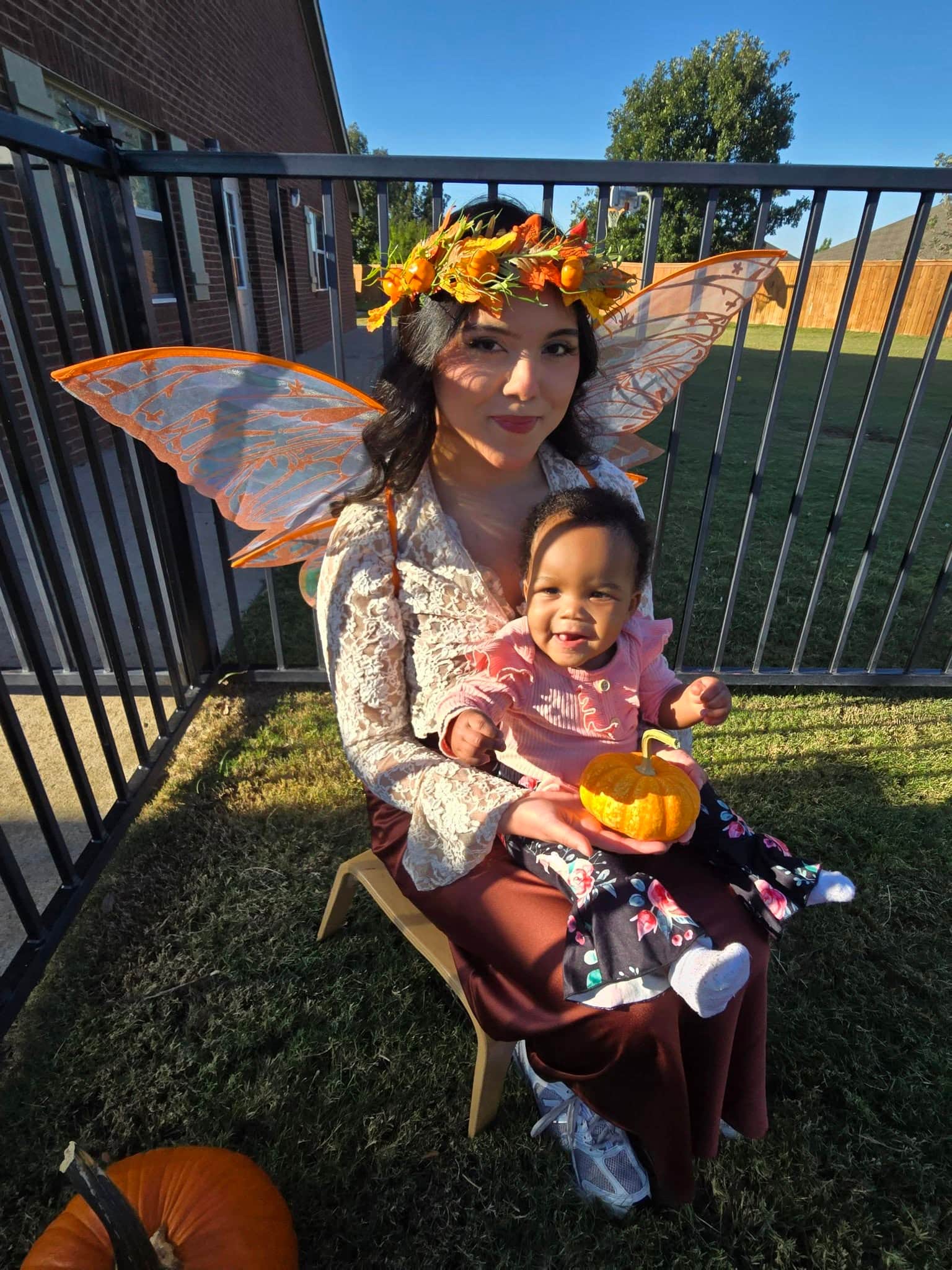 Infant girl holding a pumpkin while sitting on the Pumpkin Fairy’s lap at Primrose School at Heritage in Fort Worth, TX, celebrating fall with a fun, memorable experience at our infant daycare and preschool
