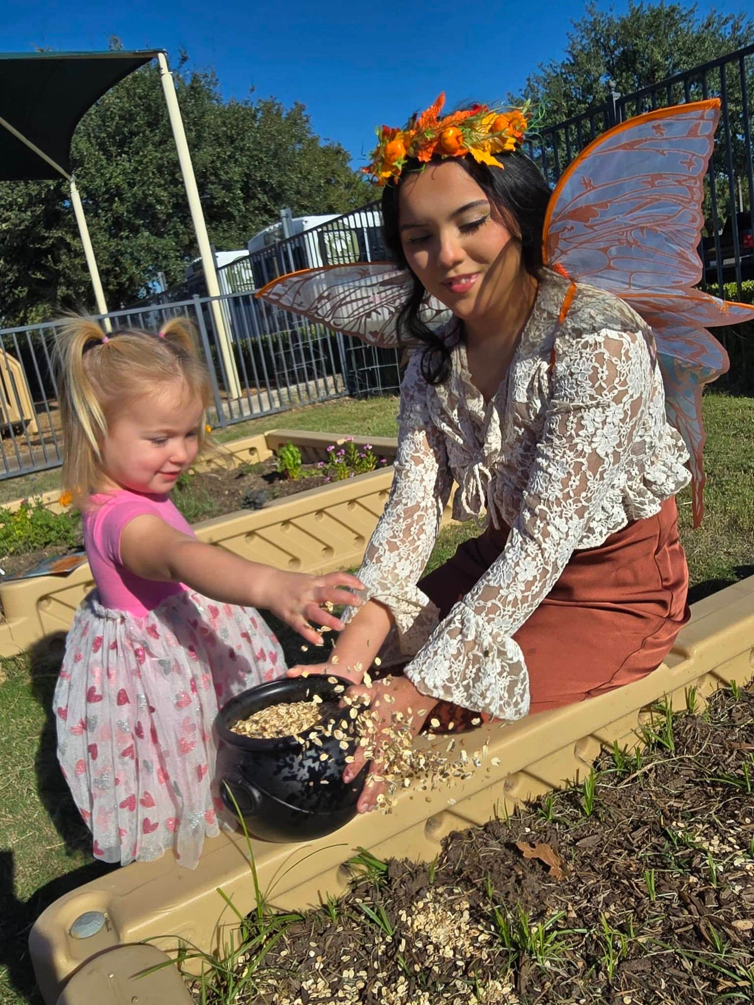 Young student scattering magical seeds with the Pumpkin Fairy in the Primrose Patch at Primrose School at Heritage in Keller, TX, enjoying a fun fall learning experience at our preschool and daycare