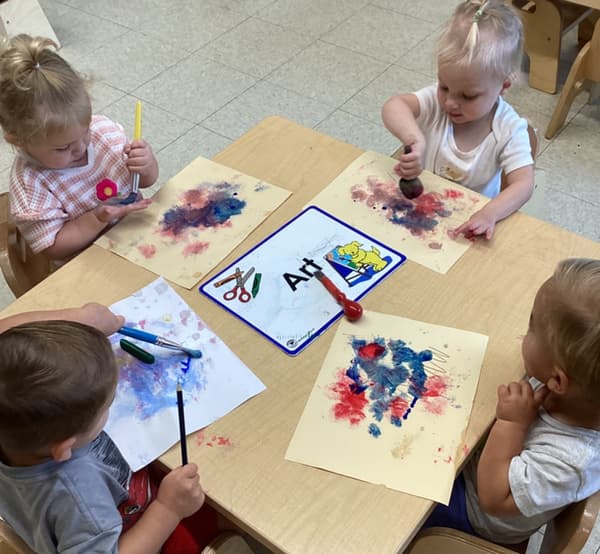 Toddlers participating in a group painting activity at Primrose School, exploring creativity, self-expression, and fine motor development through hands-on art experiences.