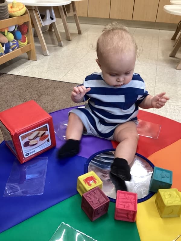 Infant engaging with sensory blocks and educational materials at Primrose School, fostering cognitive growth and motor skill development.
