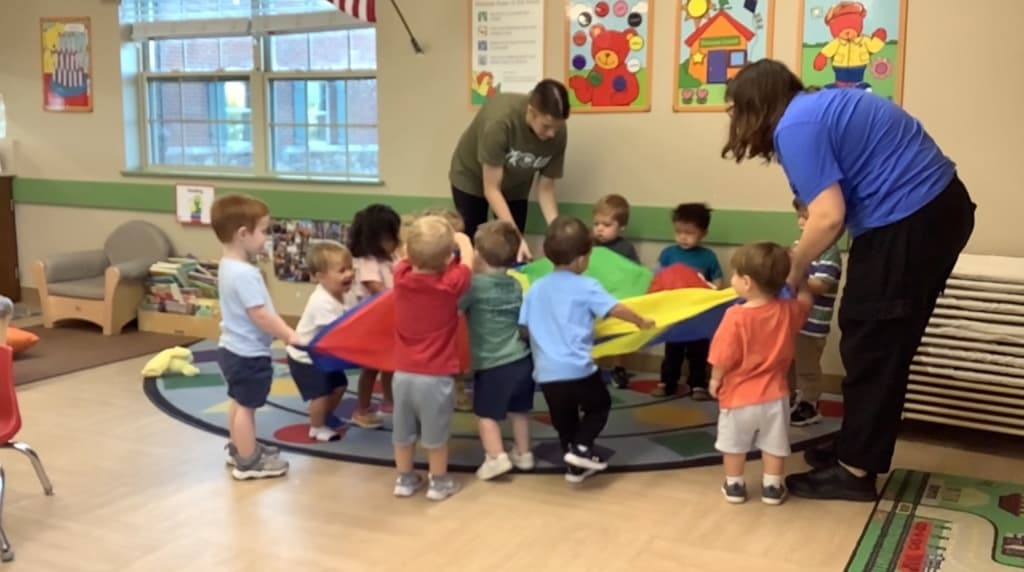 Children playing with a parachute in the classroom