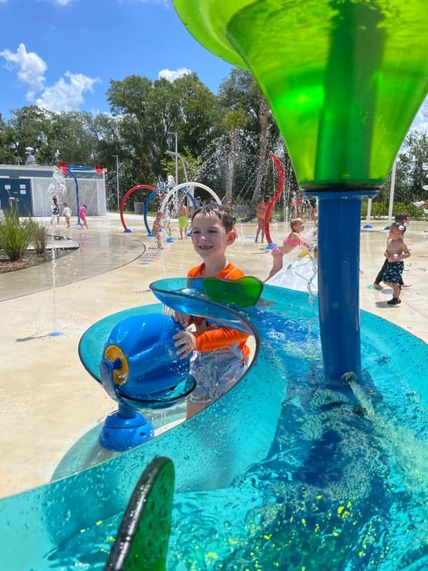 Child enjoying water play at a splash pad during a summer adventure field trip, exploring movement, sensory experiences, and outdoor fun.