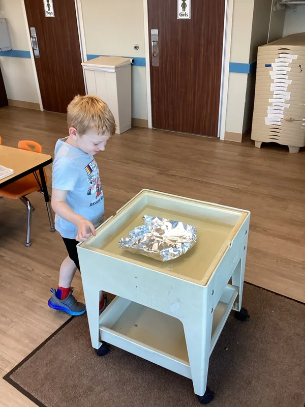 child looking at foil boat
