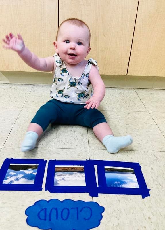 infant baby sitting in front of images of clouds learning about weather and science at Primrose in North Fort Worth.
