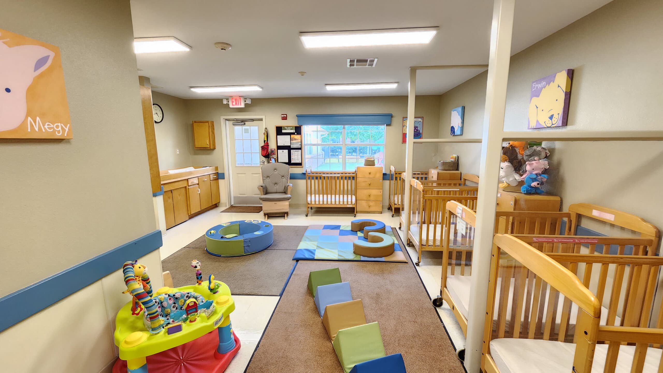 "Young Infants Room with Safe Baby Cribs, Colorful Play Equipment, and Stimulating Early Childhood Development Activities"