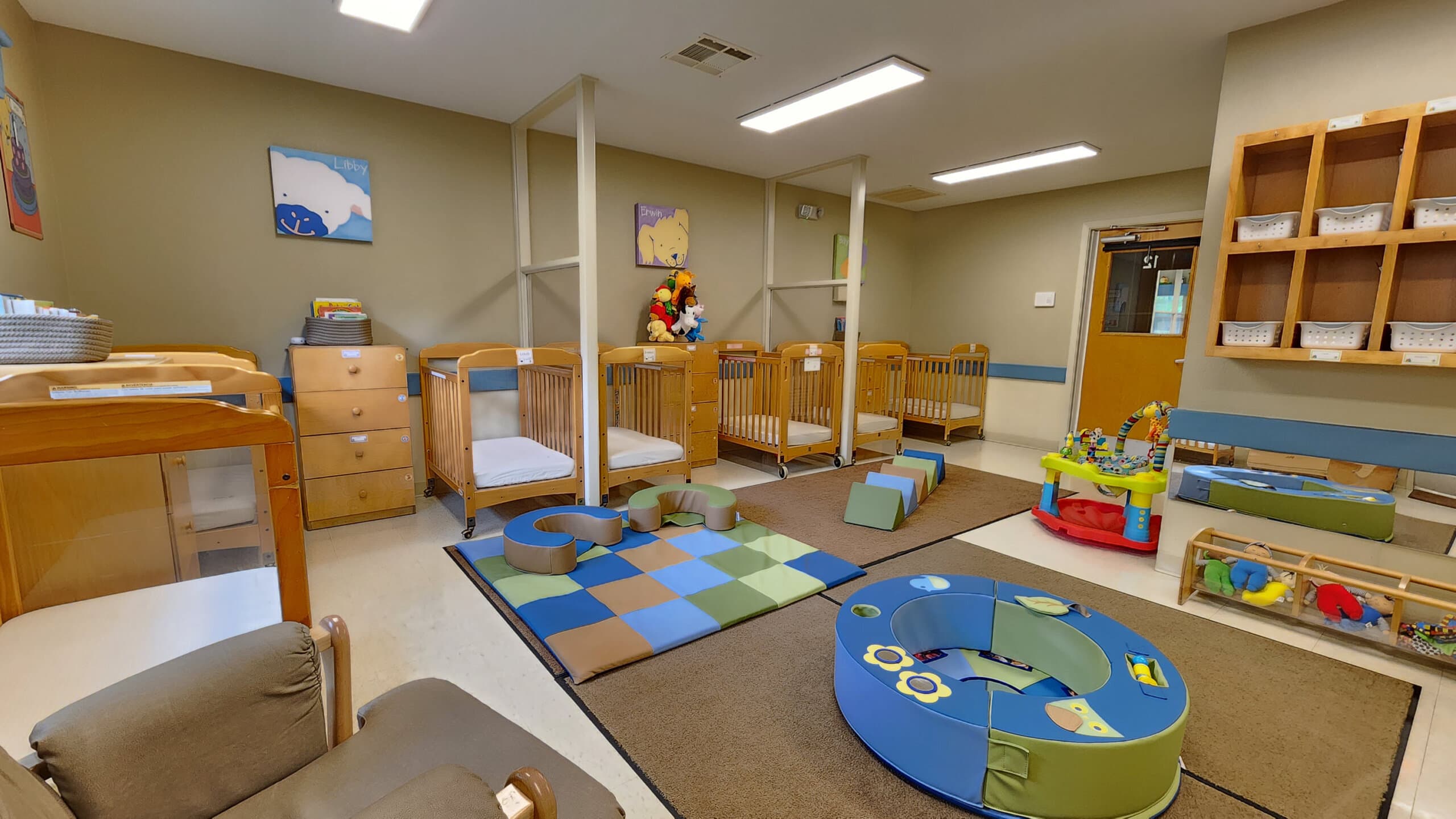 "Young Infants Room with Safe Baby Cribs, Colorful Play Equipment, and Stimulating Early Childhood Development Activities"