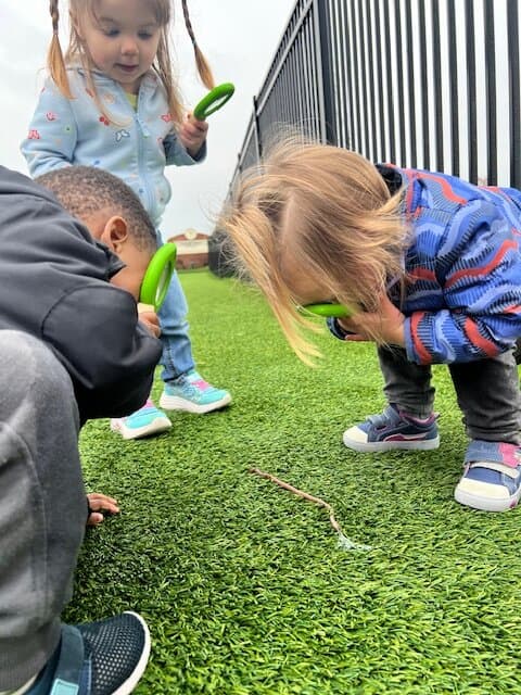 Children looking at worms with magnifying glasses