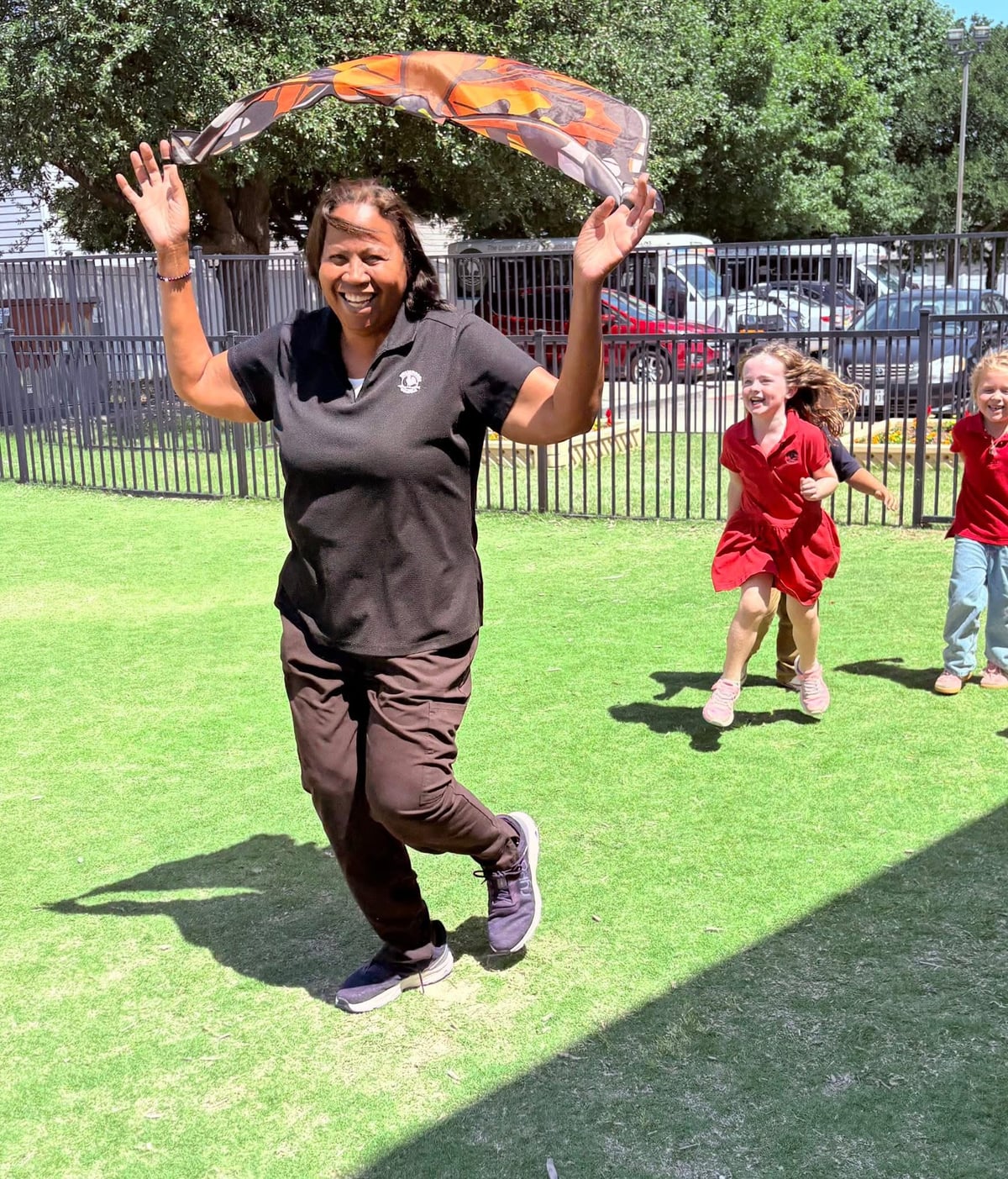 teacher running around with butterfly wings while kids chase her