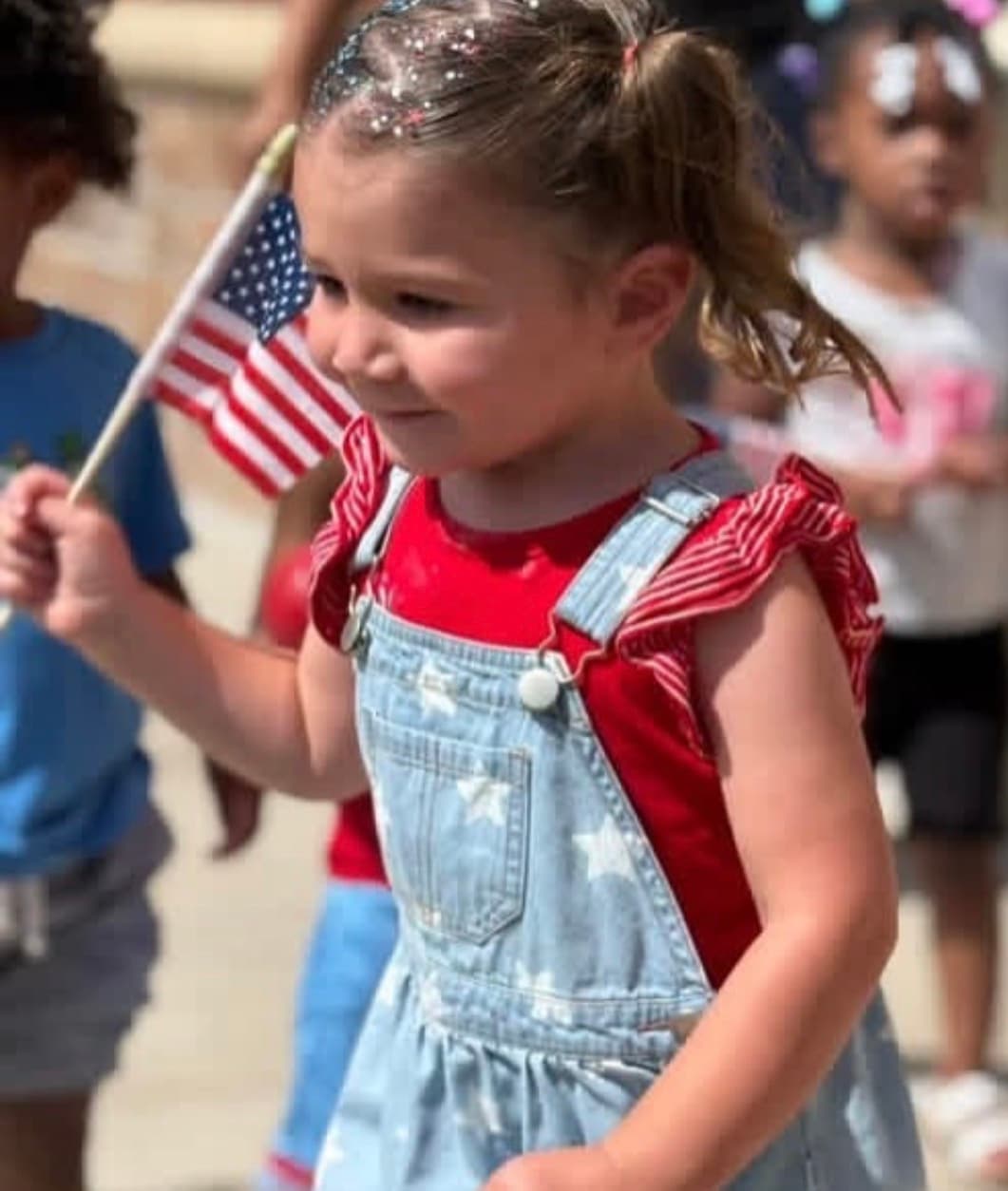 child holding a flag during 4th of july parade