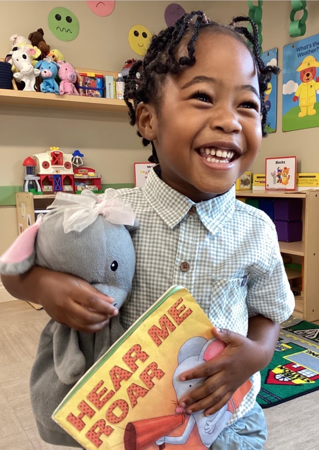 a smiling little boy, holding on to Mia the Mouse and her book, "Hear Me Roar"