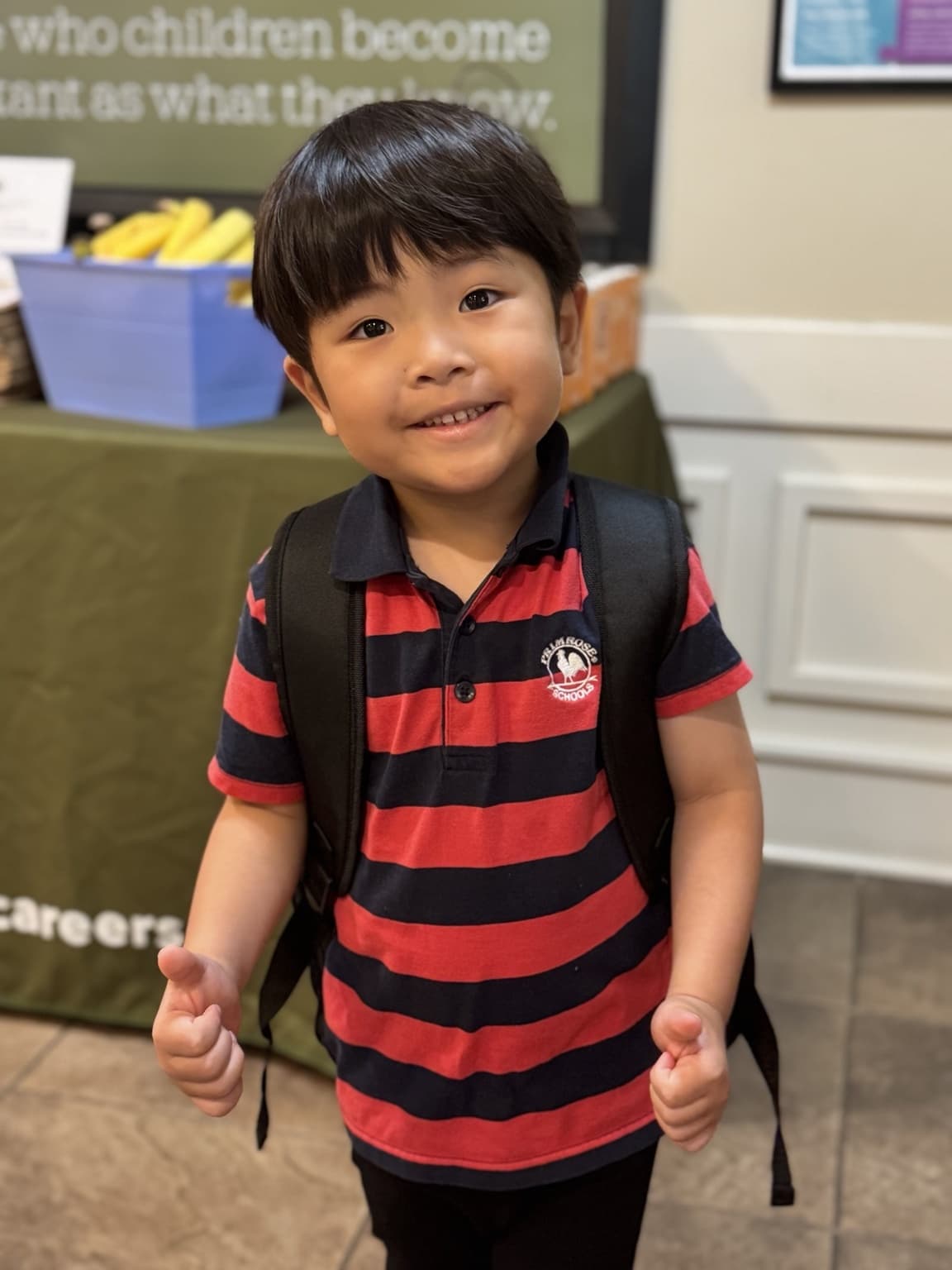 Smiling Primrose School of Braselton student wearing a backpack and giving two thumbs up, ready for a day of learning.