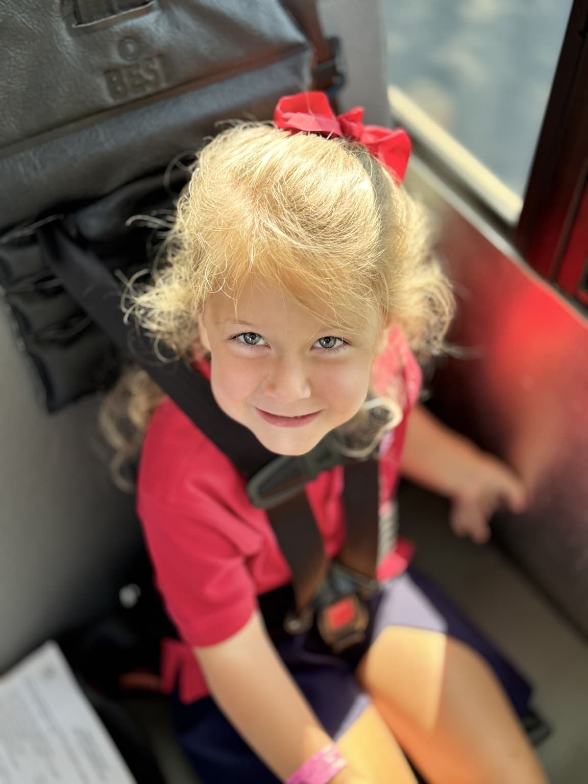 Pre-K student smiling while safely buckled into the Primrose School of Braselton bus for a field trip.