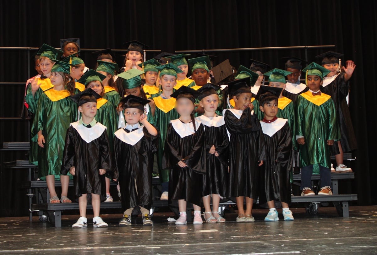 Children on stage in caps and gowns