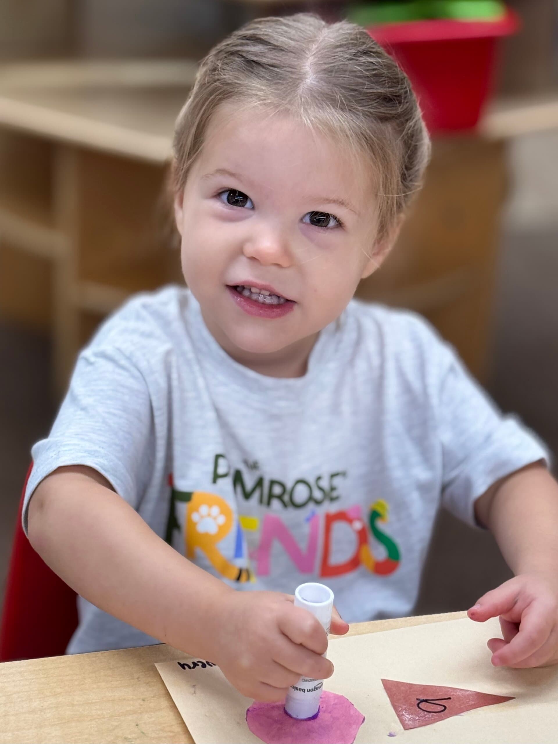 Preschool student smiling while creating an art project at Primrose School of Braselton.