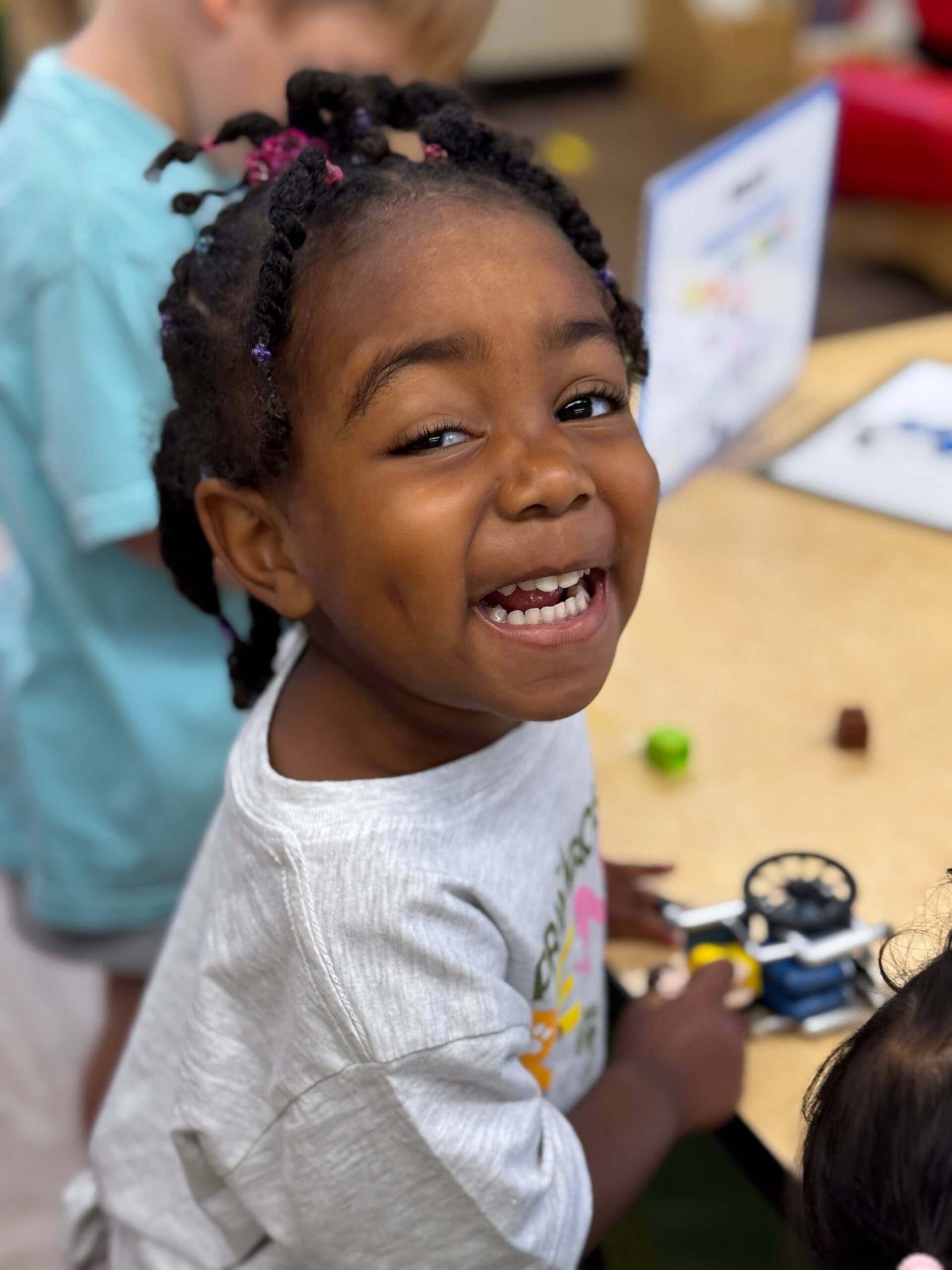 Preschool student smiling during a hands-on classroom activity at Primrose School of Braselton.