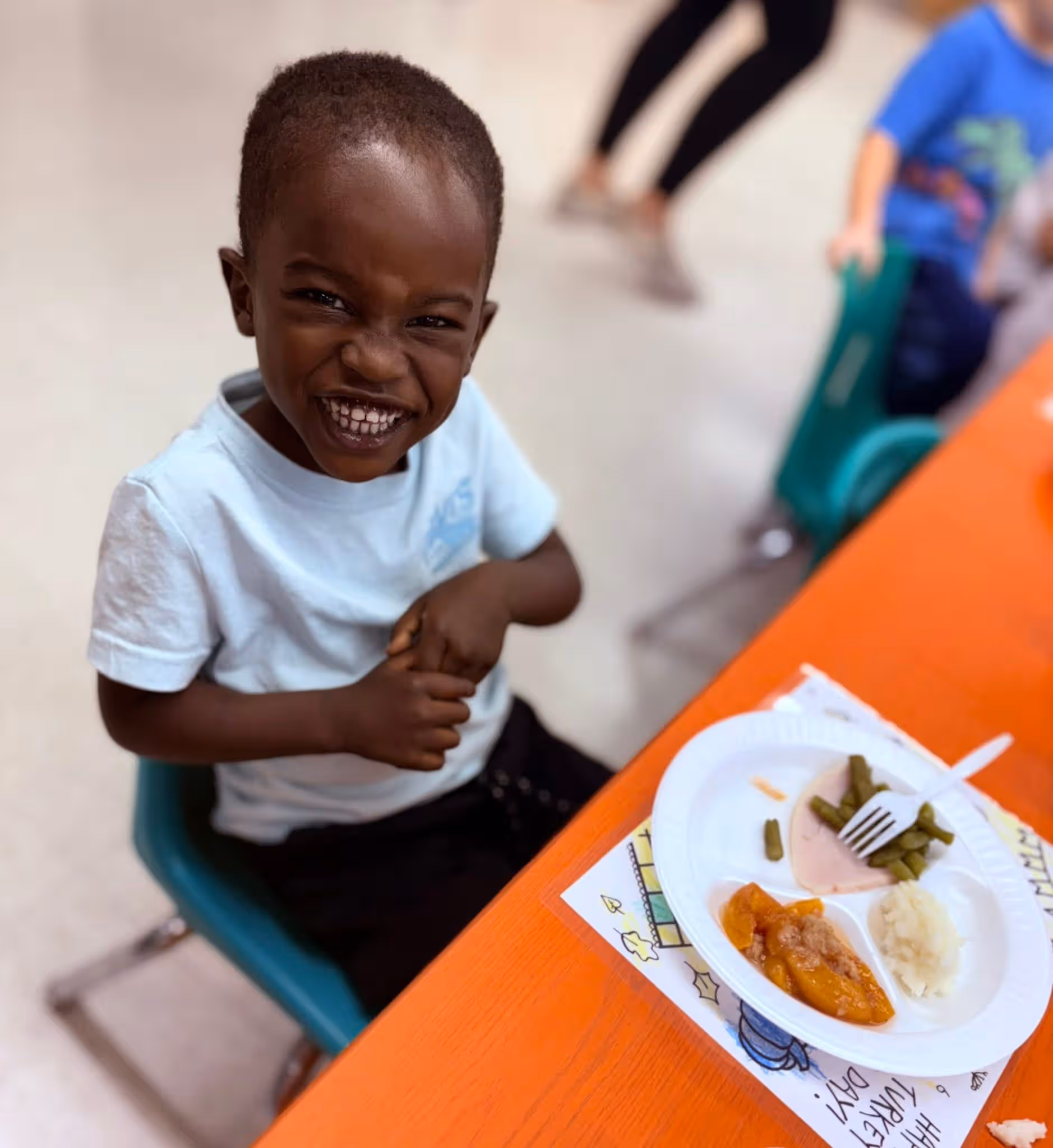 Child smiling in front of a Thanksgiving plate of food